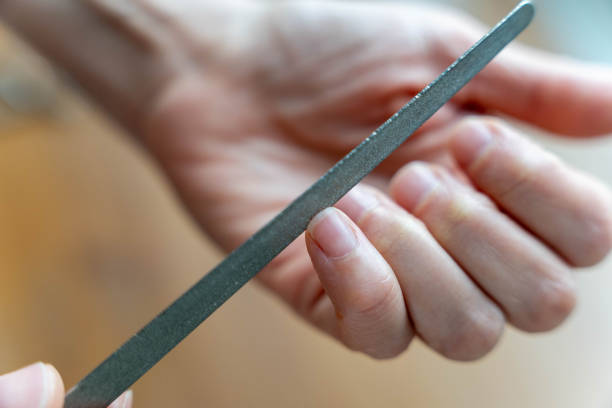 istock Manicurist filing woman's nails with precision using a nail file 2185410569