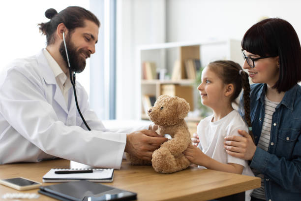istock Friendly doctor demonstrates stethoscope checkup with teddy bear for child 2185410834
