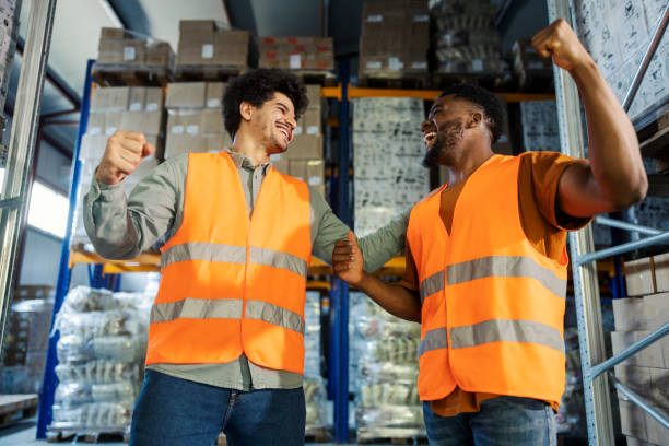 istock Cheerful diverse colleagues in protective work wear celebrating success at warehouse. 2185412837