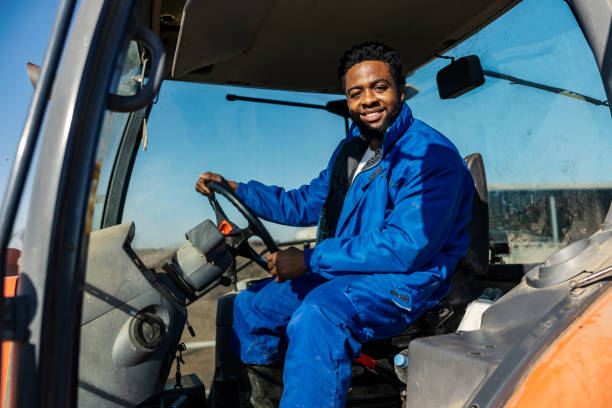 istock Smiling hardworking multicultural farmer driving a tractor at ranch and smiling at camera. 2185413043