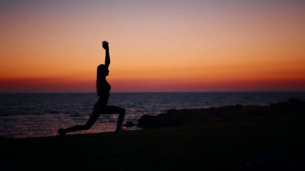 istock Active woman stretching body during sunset over ocean 2185417997