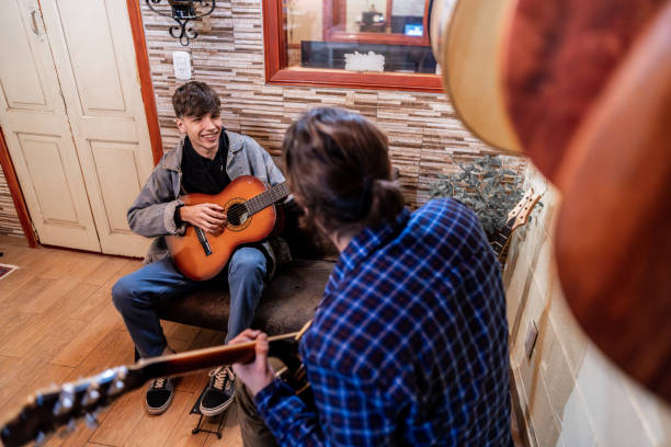 istock Student playing guitar with teacher's help in a music school 2185418063