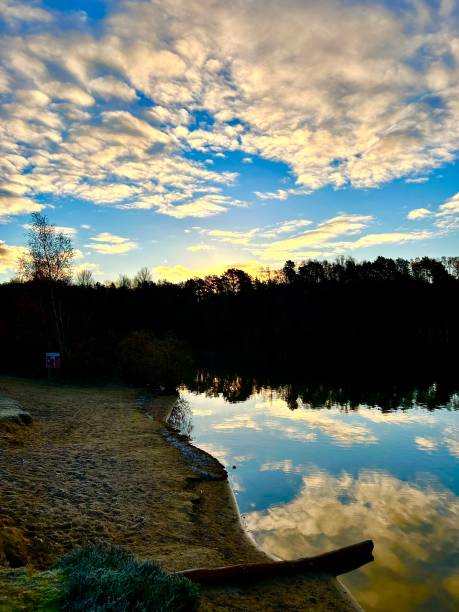 Fluffy clouds, through a piercing blue sky, glistening lake and forest view