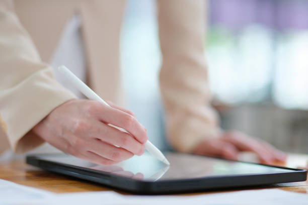 istock Close-up of hand signing electronic documents on a tablet with a digital pen for online workflows 2185420317