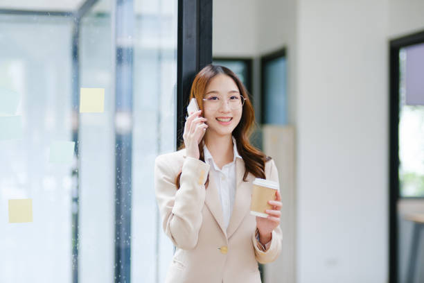 istock Businesswoman holding coffee while making a phone call during a break from her work 2185420331