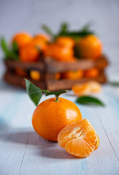 istock Fresh tangerines with leaves in a wooden crate on a blue table 2185422498