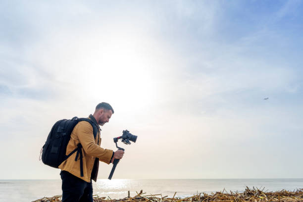 istock Camera Operator Filming Flood-Damaged Vegetation and Debris Washed Ashore on a Beach Using a Gimbal 2185422581