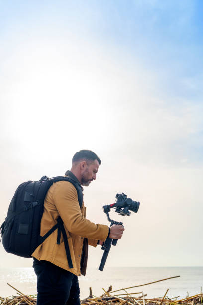 istock Camera Operator Filming Flood-Damaged Vegetation and Debris Washed Ashore on a Beach Using a Gimbal 2185422587