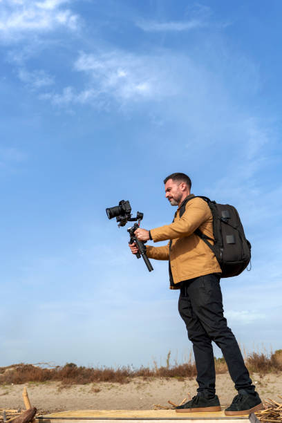 istock Camera Operator Filming Flood-Damaged Vegetation and Debris Washed Ashore on a Beach Using a Gimbal 2185422614