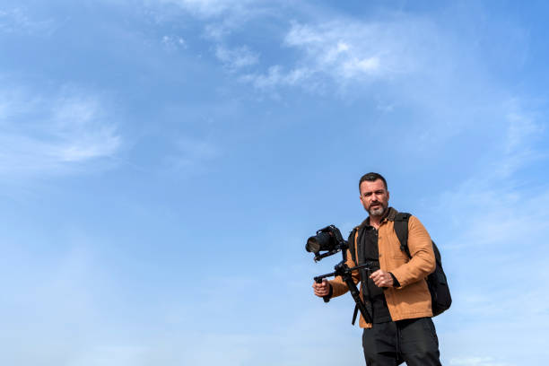 istock Male Camera Operator Filming with a Gimbal Against a Clear Blue Sky 2185422626