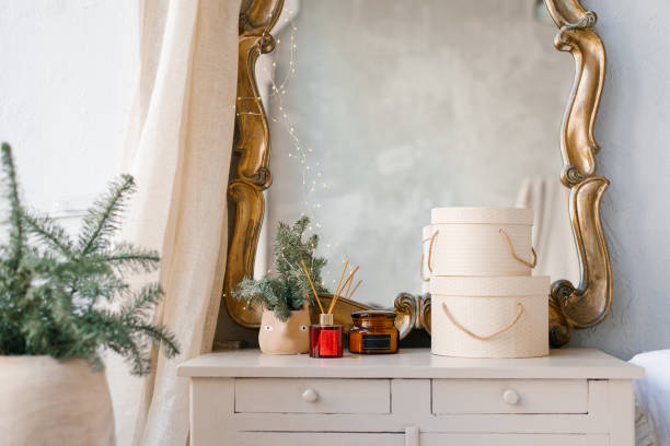 istock A Christmas tree in a pot, a diffuser, a candle and round gift boxes stand on a light chest of drawers in the living room or bedroom in the interior of the house 2185425604