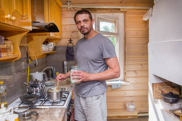 A European man is preparing food at the stove. Life of ordinary people.
