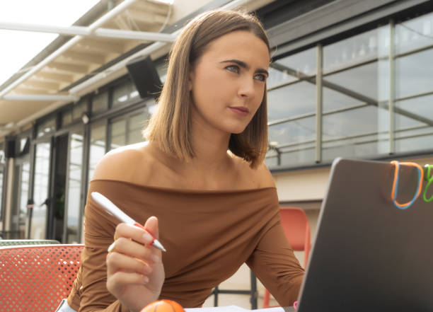 istock Young woman with a computer, taking notes and using objects, rubber bands, toys, and assistive devices for concentration. 2185430847