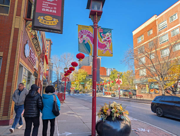 Calgary, Canada - October 24, 2024: Pedestrians walk on the 100-block of 2nd Avenue Southeast past retailers and restaurants. Banners and red lanterns line Chinatown. Autumn afternoon with a clear sky.