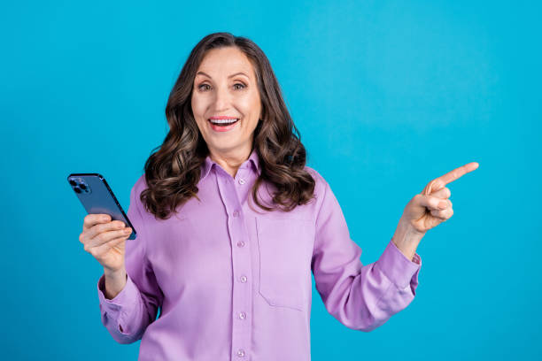istock Photo of cheerful pretty lady dressed puple blouse reading modern gadget showing empty space isolated blue color background 2185431301
