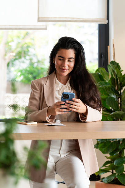 istock Young hispanic businesswoman using mobile phone in modern office 2185432000