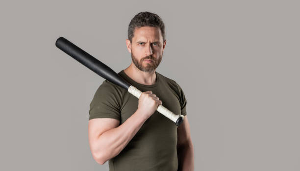 istock criminal man threatening with bat standing in studio. criminal man with bat isolated on grey 2185432250