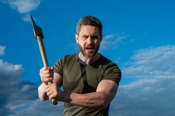 man threaten with axe. shouting man hold ax. brutal man on sky background.