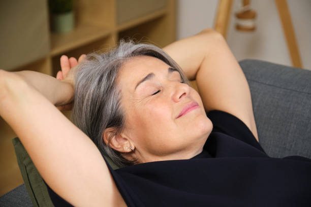 istock Relaxed mature woman resting on sofa with hands behind head 2185433984