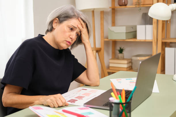 istock Stressed mature adult woman having headache while working from home 2185435373