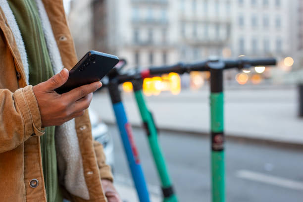 istock Man using smartphone app to rent electric scooter in urban setting 2185442355