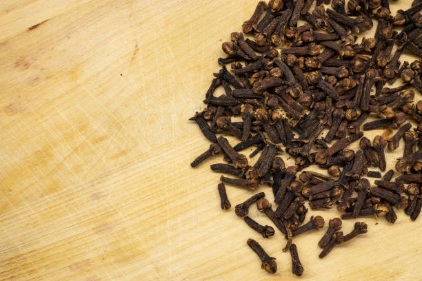 Aromatic dried cloves scattered on a wooden surface, ready to enhance culinary creations