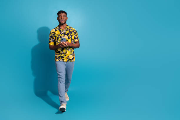 istock Happy young man in a stylish printed shirt walking on a blue background 2185445516