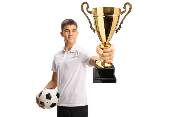 istock Guy holding a football and showing a gold trophy cup 2185449610