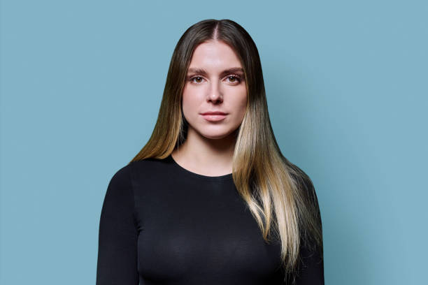 istock Portrait serious young woman looking at camera on blue studio background 2185451206