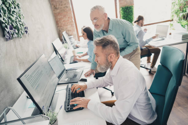 istock Photo of coworking project teamwork people senior men computer work together conference meeting successful nice light office 2185454811