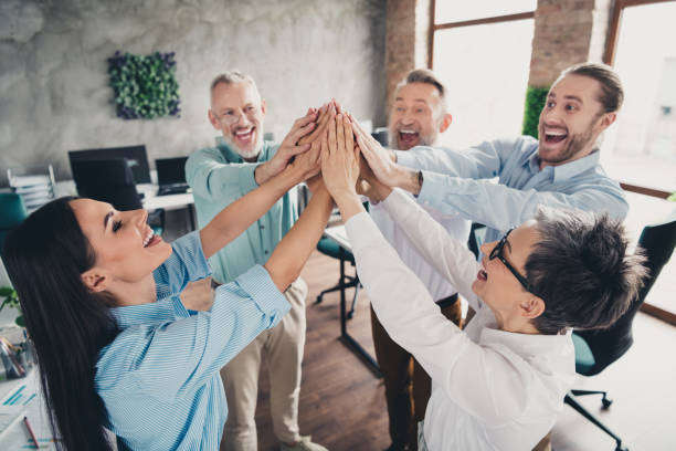 istock Photo of teamwork people working together raise hands support high five comfortable modern office loft room interior indoors workspace 2185454868