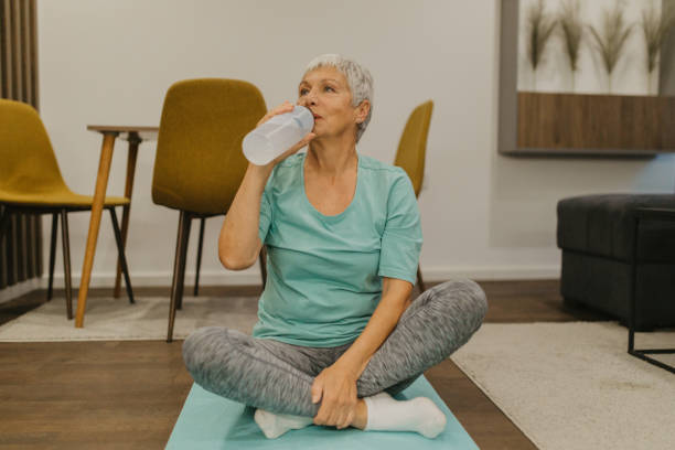istock Senior woman refreshing with water while exercising at home 2185456316