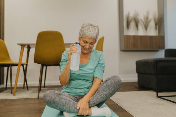 istock Senior woman refreshing with water while exercising at home 2185456319