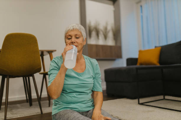 istock Senior woman refreshing with water while exercising at home 2185456362