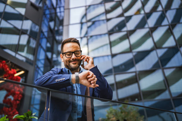 istock businessman talk on cellphone stand in front a modern glass building 2185458806