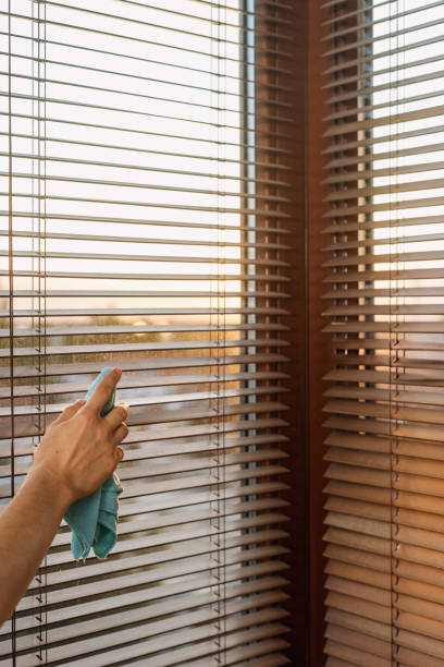istock Cleaning window blinds in a bright room during sunset for a clearer view 2185464178
