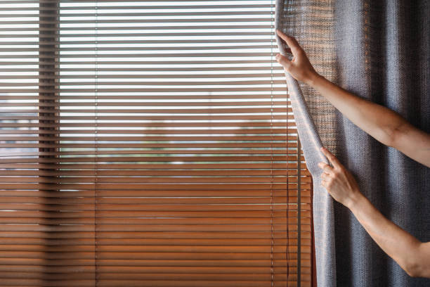 istock Person opening blinds to let sunlight in on a bright morning 2185464217
