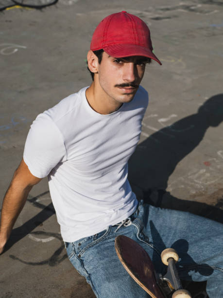 istock Young skater sitting with skateboard in urban skate park setting 2185465286