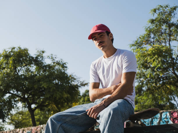 istock Young man with skateboard relaxing in urban park setting 2185465347