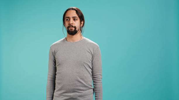 Portrait of serious man standing isolated against blue studio background