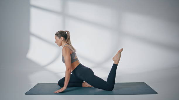 istock Sport woman performing yoga pose at light studio. Athletic model stretching 2185465440