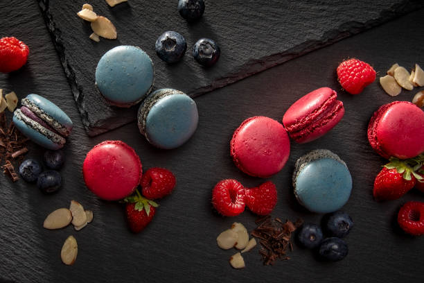 Blueberry and Raspberry Macaroon cookies sweet pastry on black slate background