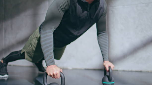 istock Muscular sportsman making push ups in plank using kettlebells in studio closeup 2185470318