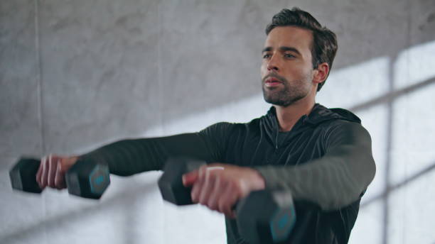 istock Focused man lifting dumbbells doing workout in loft gym closeup. Guy training 2185470852