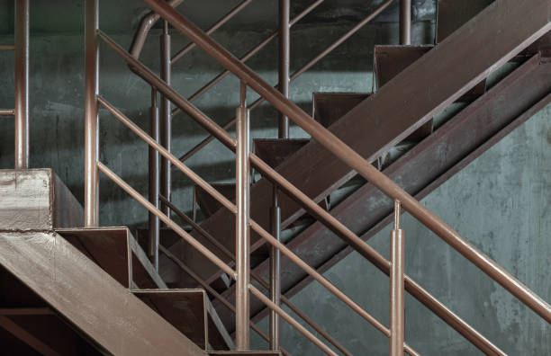 Side view of Old metal steps with handrails against concrete wall background. Vertical view of Steel ladder, Space for text, Selective Focus.