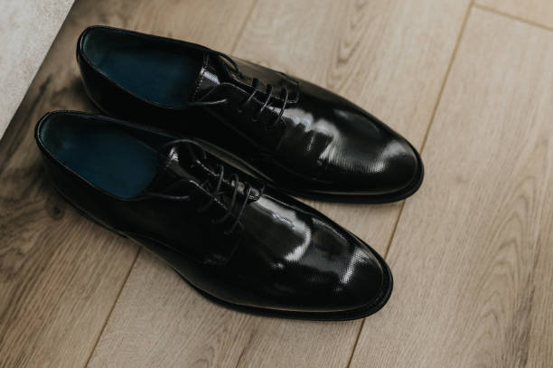 Black dress shoes are neatly arranged on an intricate patterned rug, showcasing their polished surface and elegant design in a cozy indoor setting.