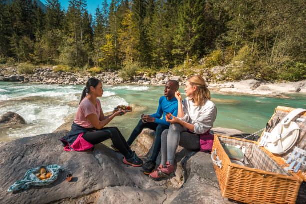 istock Diverse Group of Friends Enjoying Picnic During Hike by River 2185477151