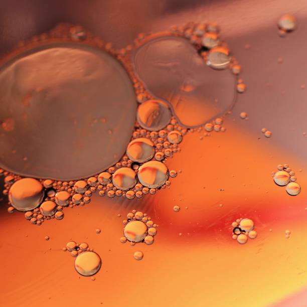 istock Different Sized Droplets of Oil on Water on a Swirled Orange background 2185477589