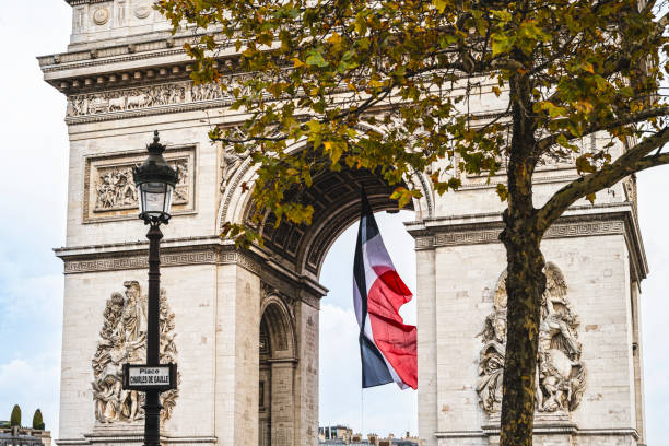 Paris, France : large French flag flying under the Arc de Triomphe for commemoration days (world wars, Bastille day).
