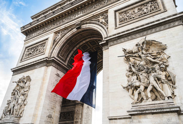 Paris, France : large French flag flying under the Arc de Triomphe for commemoration days (world wars, Bastille day).